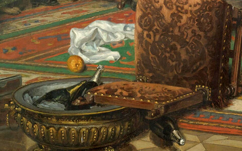 A silver champagne bucket with bottles on the floor, an overturned footstool, a fallen napkin and an orange rolling on the carpet