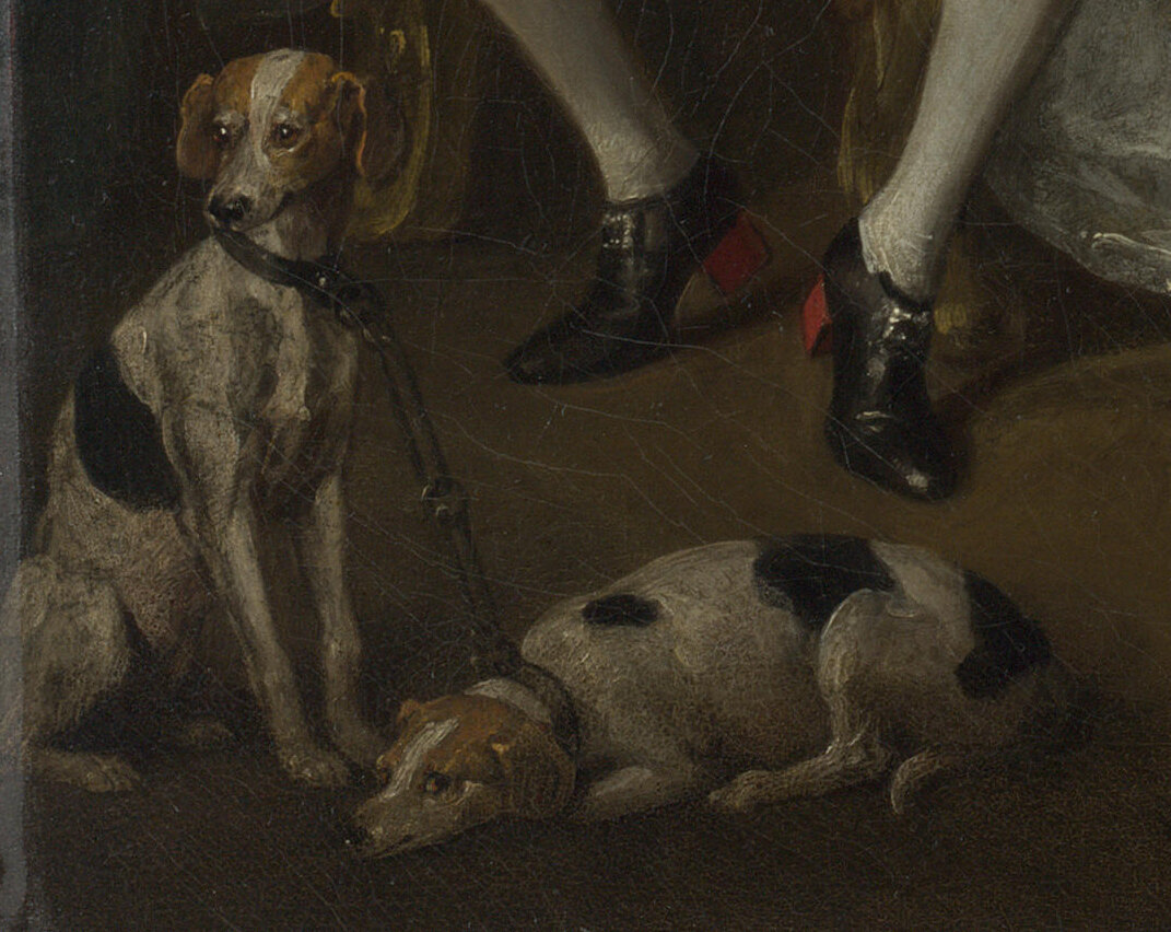 Two dogs at the couple's feet chained together at the neck, one lying down and looking away