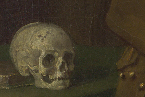 A human skull on a green cloth on a table, with a book beneath it