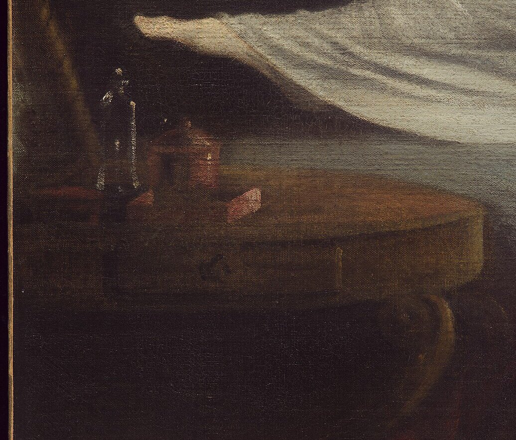 A small table by the bed with a mirror, bottles and a book