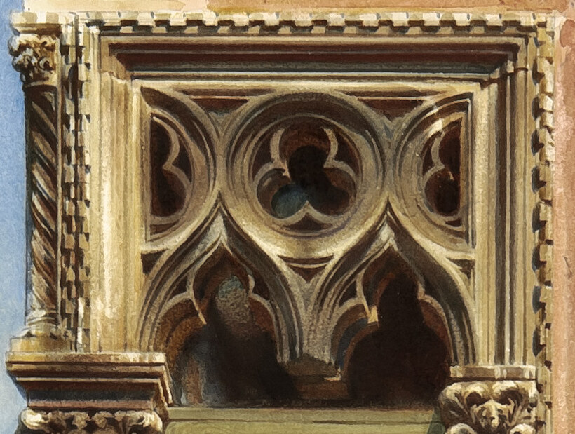 The carved Gothic tracery of quatrefoils and pointed arches above the balcony window