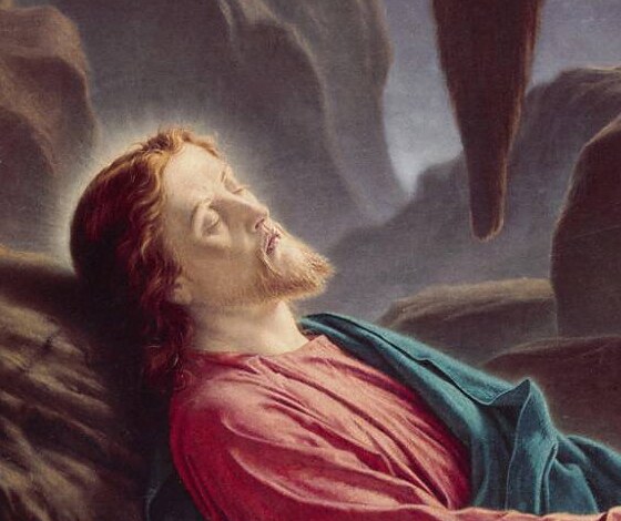 The sleeping face of Christ with a faint halo, resting against the rock
