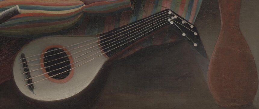 The mandolin and the water jar lying on the sand beside the sleeping woman