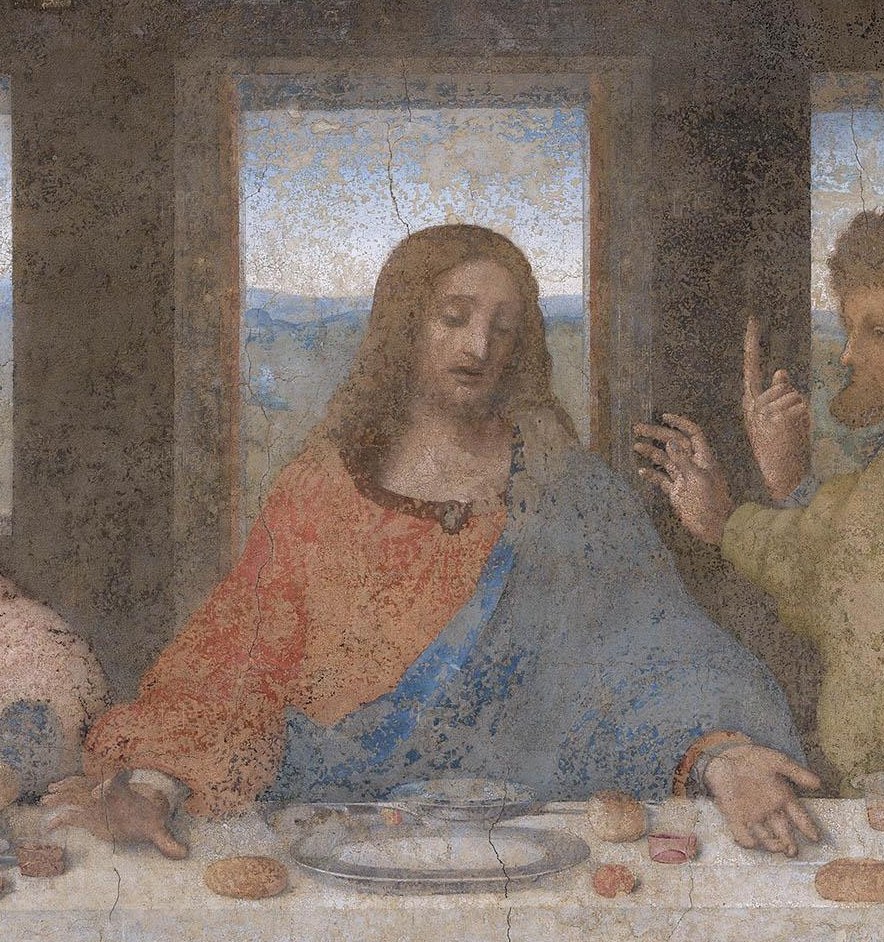 Jesus at the centre of The Last Supper, his arms spread on the table, framed by the bright window behind his head