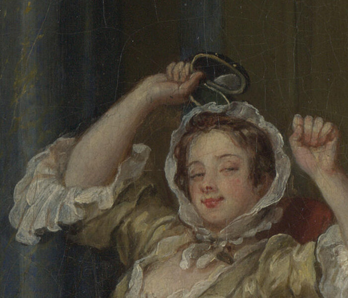 The wife raising her arms with a small mirror in one hand, smiling