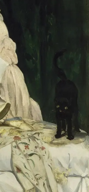 Black cat with an upright tail at the end of Olympia’s bed