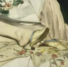 A slipper and patterned bedding beside Olympia’s feet