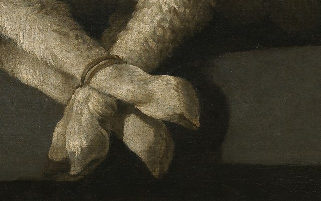 The lamb's four hooves bound together with a thin cord at the edge of the stone ledge