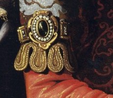 A gold armlet set with pearls and a dark stone on Saint Casilda's red sleeve